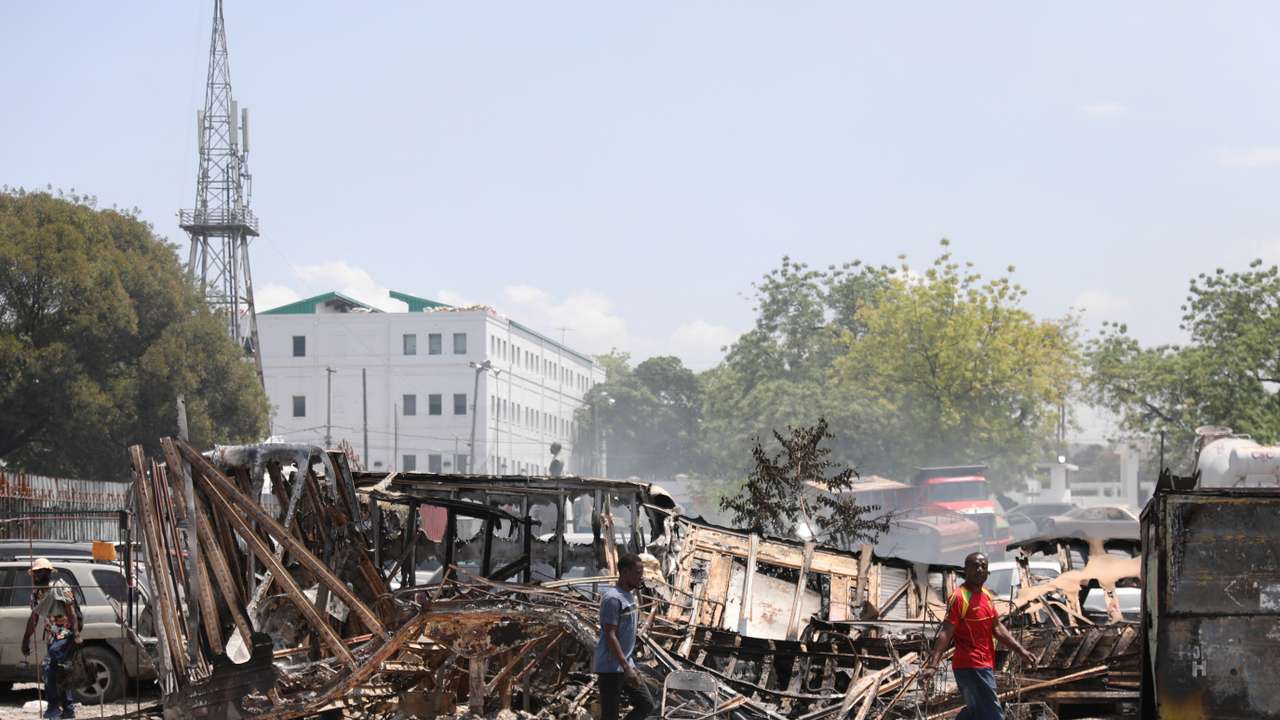 People walk past remains of vehicles after they were set on fire by gangs, in Port-au-Prince