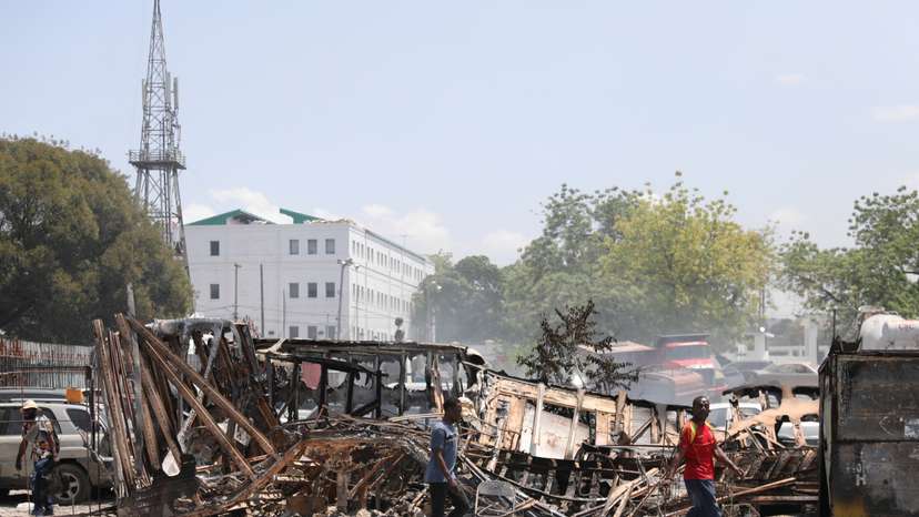 People walk past remains of vehicles after they were set on fire by gangs, in Port-au-Prince