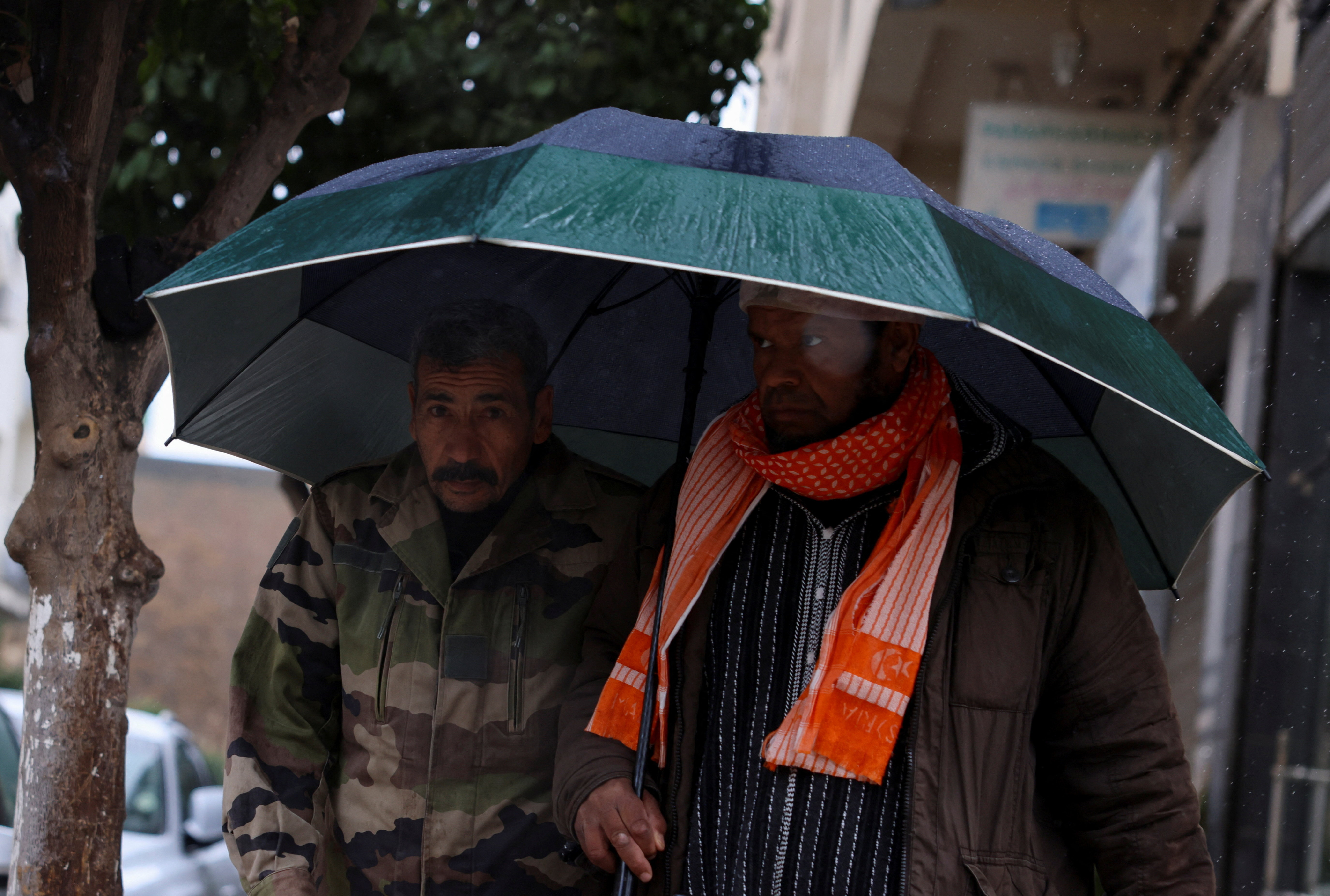 FILE PHOTO: People walk through rain and cold weather in the Moroccan city of Fes