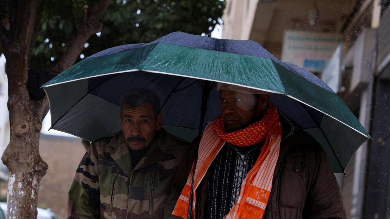 FILE PHOTO: People walk through rain and cold weather in the Moroccan city of Fes