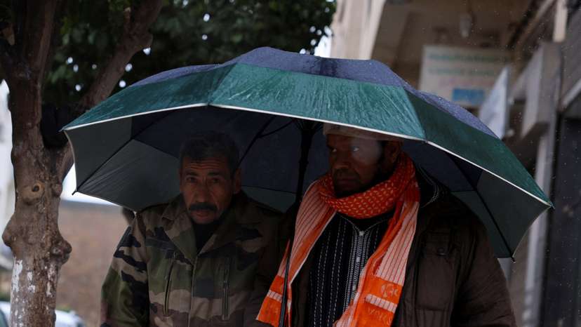 FILE PHOTO: People walk through rain and cold weather in the Moroccan city of Fes