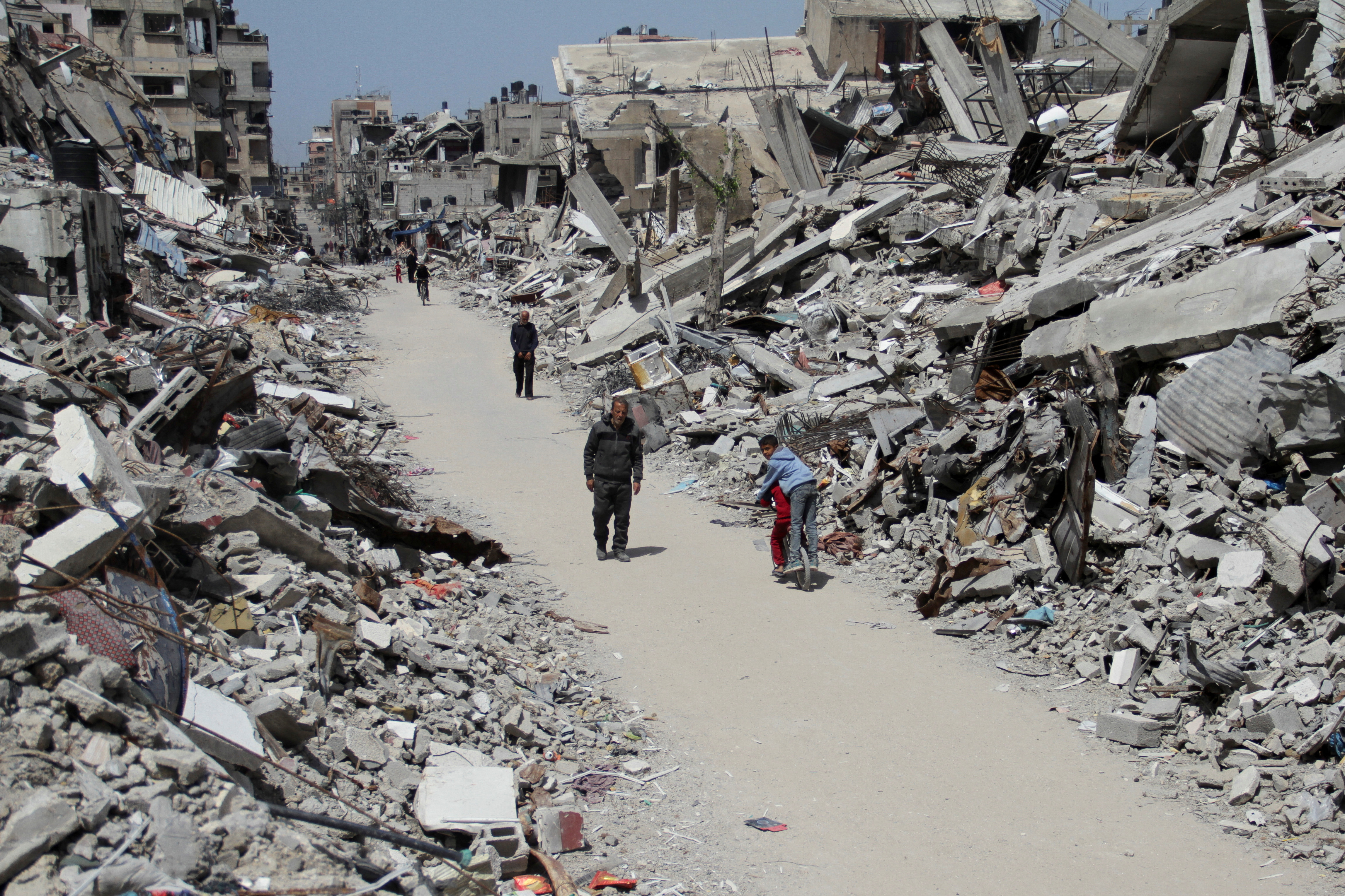 Palestinians walk past the ruins of houses and buildings destroyed during Israel’ military offensive, in the northern Gaza Strip