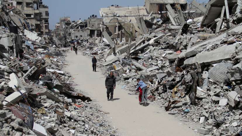 Palestinians walk past the ruins of houses and buildings destroyed during Israel’ military offensive, in the northern Gaza Strip