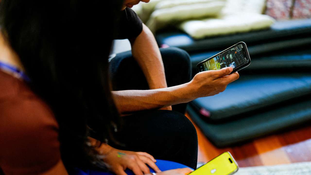 School students pose with their mobile showing social media applications in Melbourne