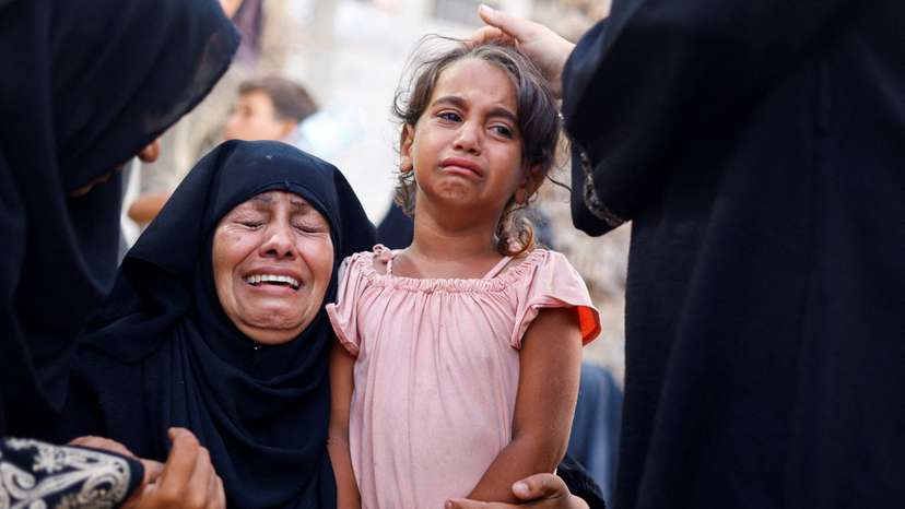 A woman and a girl react following an Israeli strike that hit a tent camp, in Al-Mawasi area