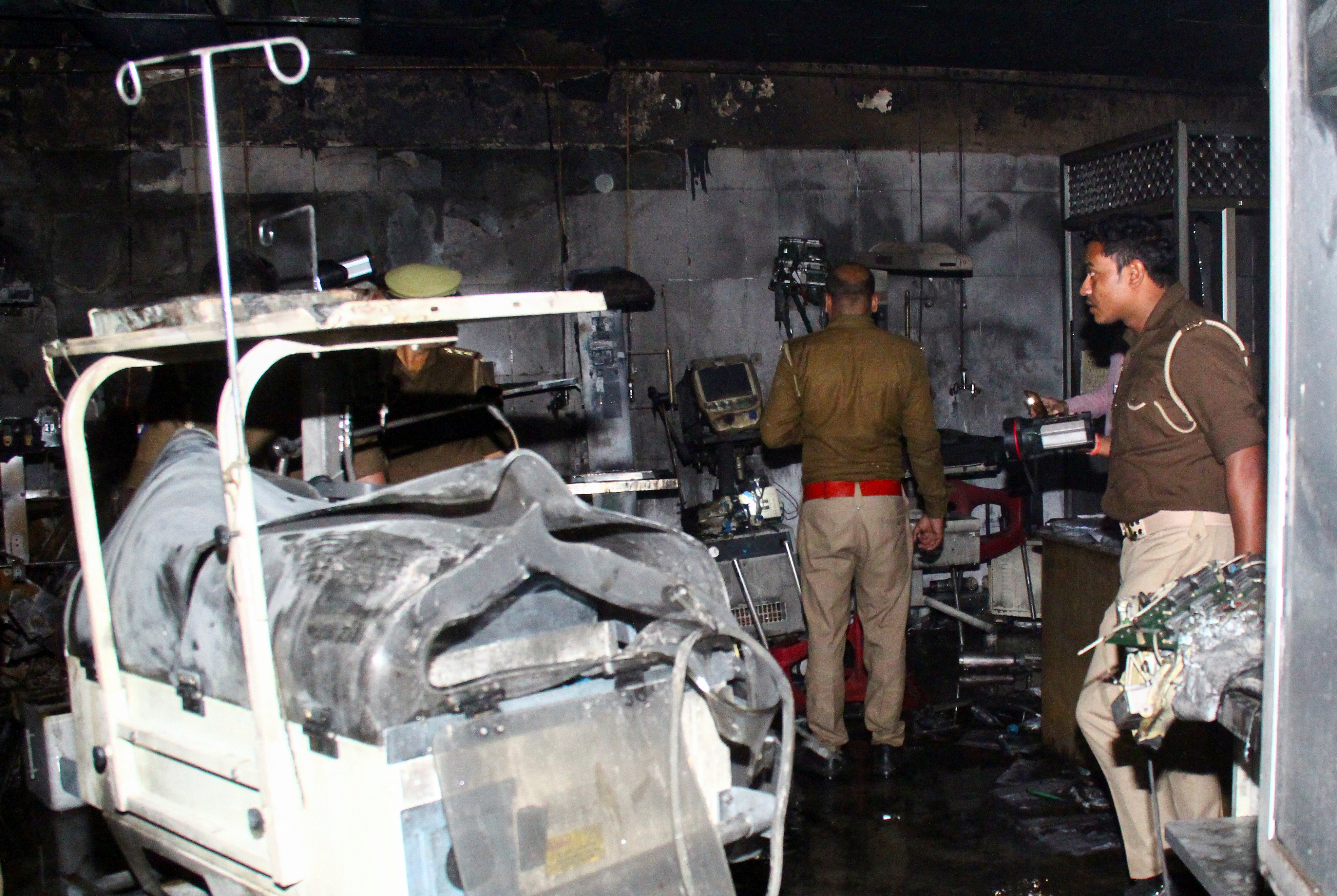 Police officers examine the damaged neonatal intensive care unit after a fire broke out at the Maharani Laxmibai Medical College in Jhansi district