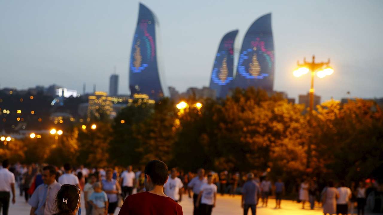 A girl, draped in Azerbaijan's national flag, walks with a boy on a street in downtown Baku
