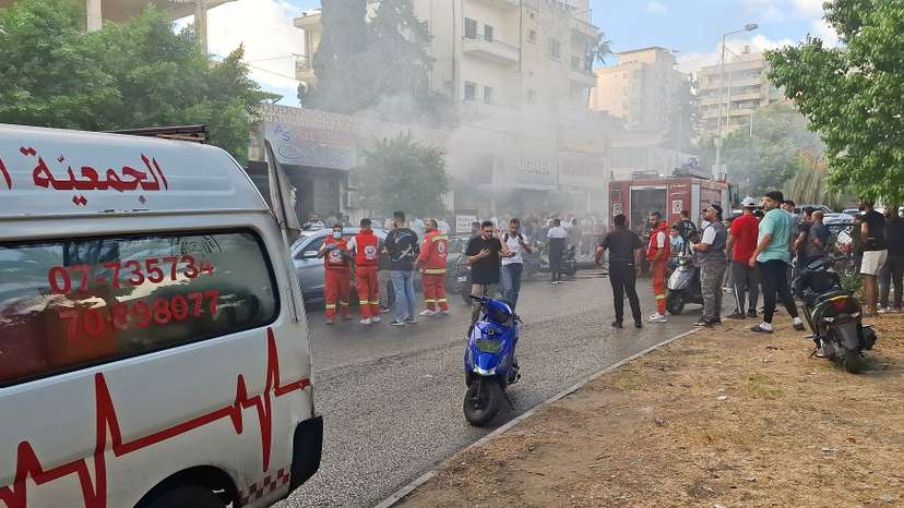 Smoke rises from a mobile shop as civil defence members gather in Sidon