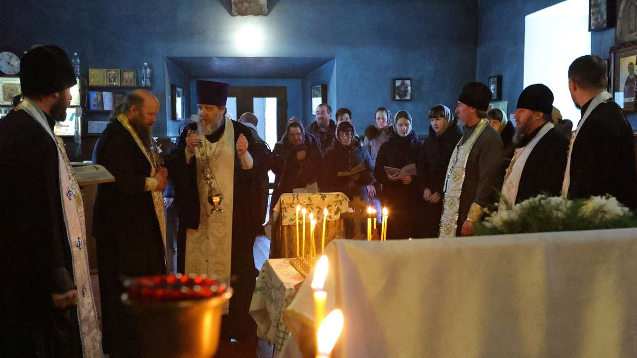 An Orthodox priest conducts a service for those killed in the crash of the Russian Ilyushin Il-76 military transport plane, in Belgorod Region