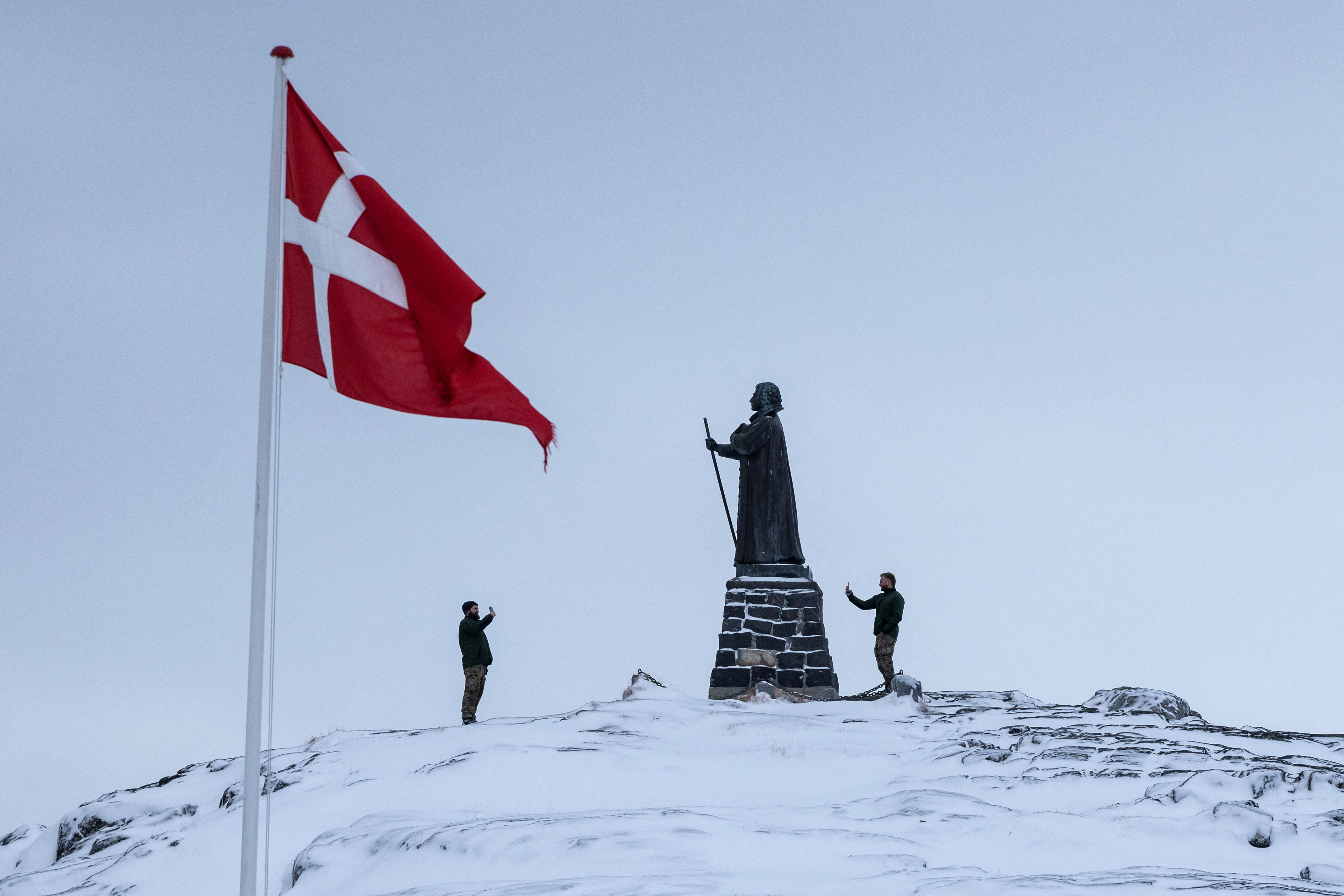 Danish soldiers take pictures next to the statue of Hans Egede, at Nuuk's old harbour