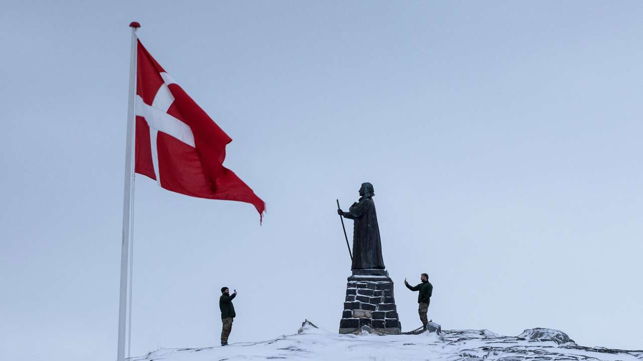 Danish soldiers take pictures next to the statue of Hans Egede, at Nuuk's old harbour