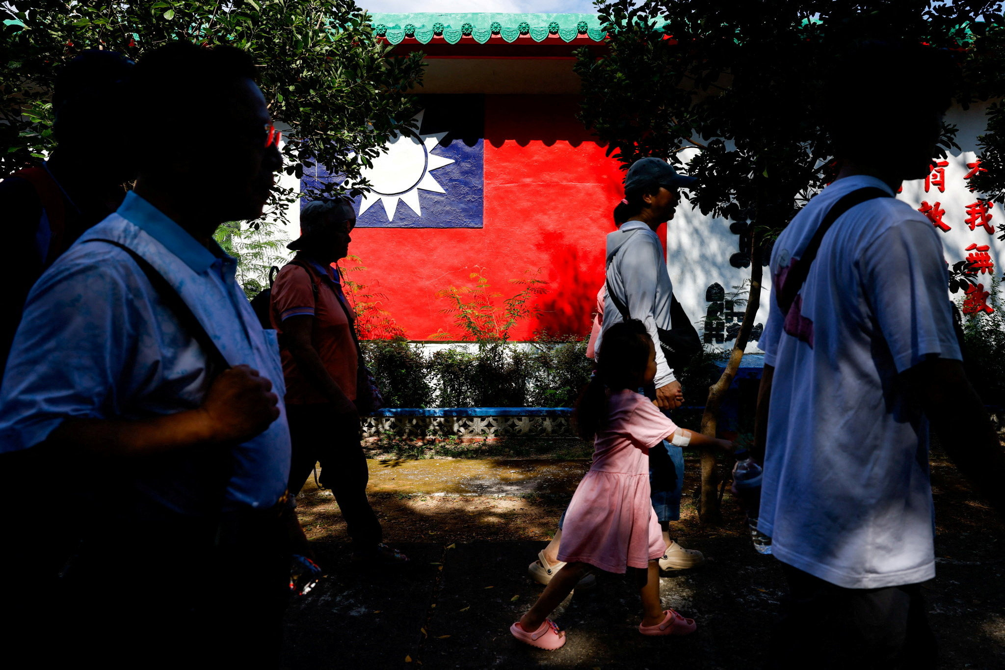 Tourists walk past a wall painted with a Taiwan flag, on Dadan Island