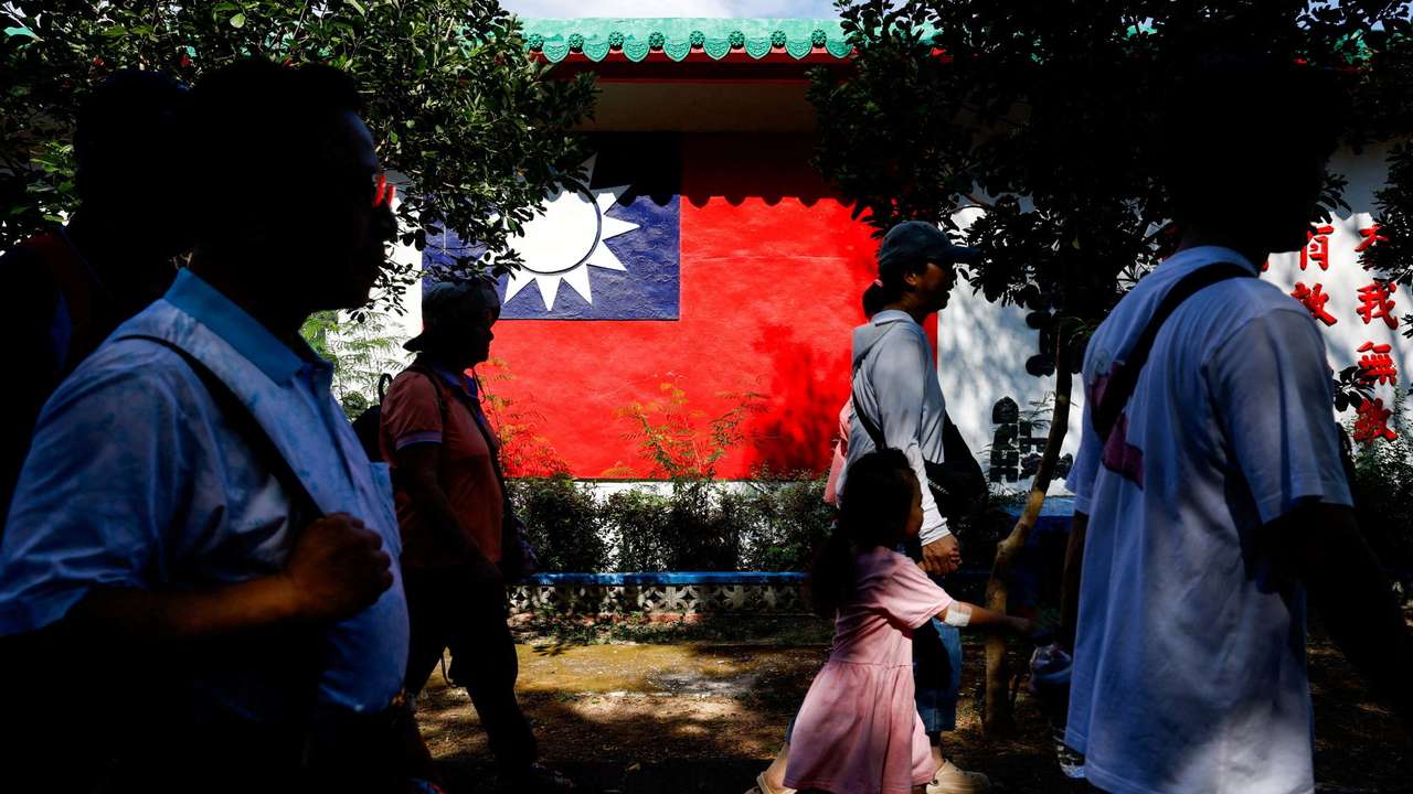 Tourists walk past a wall painted with a Taiwan flag, on Dadan Island