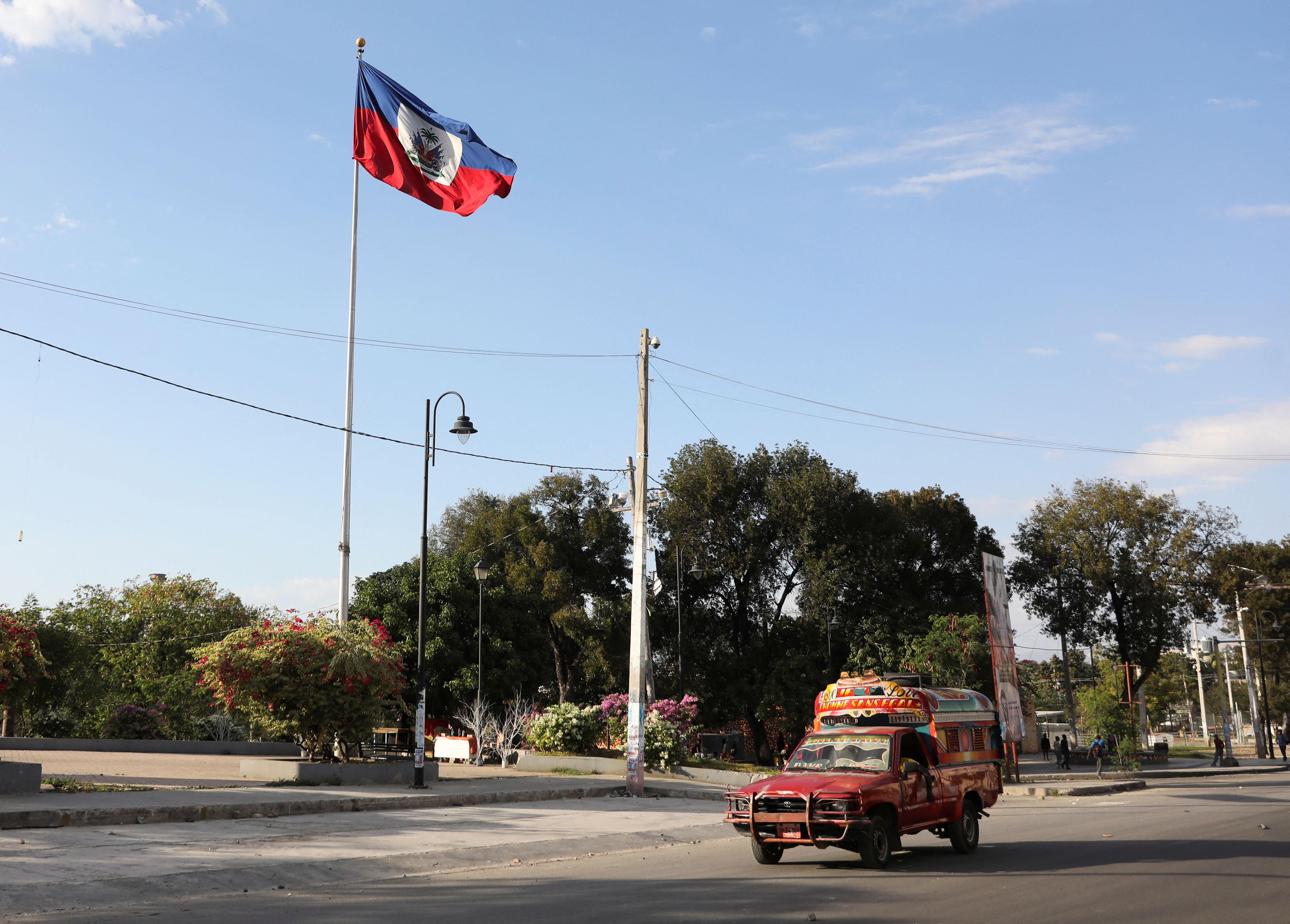 FILE PHOTO: A vehicle drives past Haiti's national flag, in Port-au-Prince