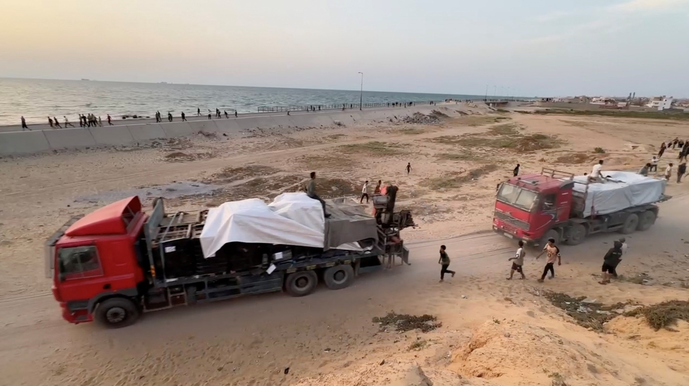 Trucks carrying aid delivered into Gaza via a U.S.-built pier move, as seen from central Gaza Strip