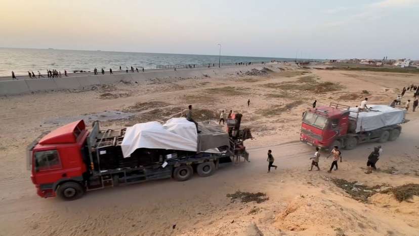 Trucks carrying aid delivered into Gaza via a U.S.-built pier move, as seen from central Gaza Strip