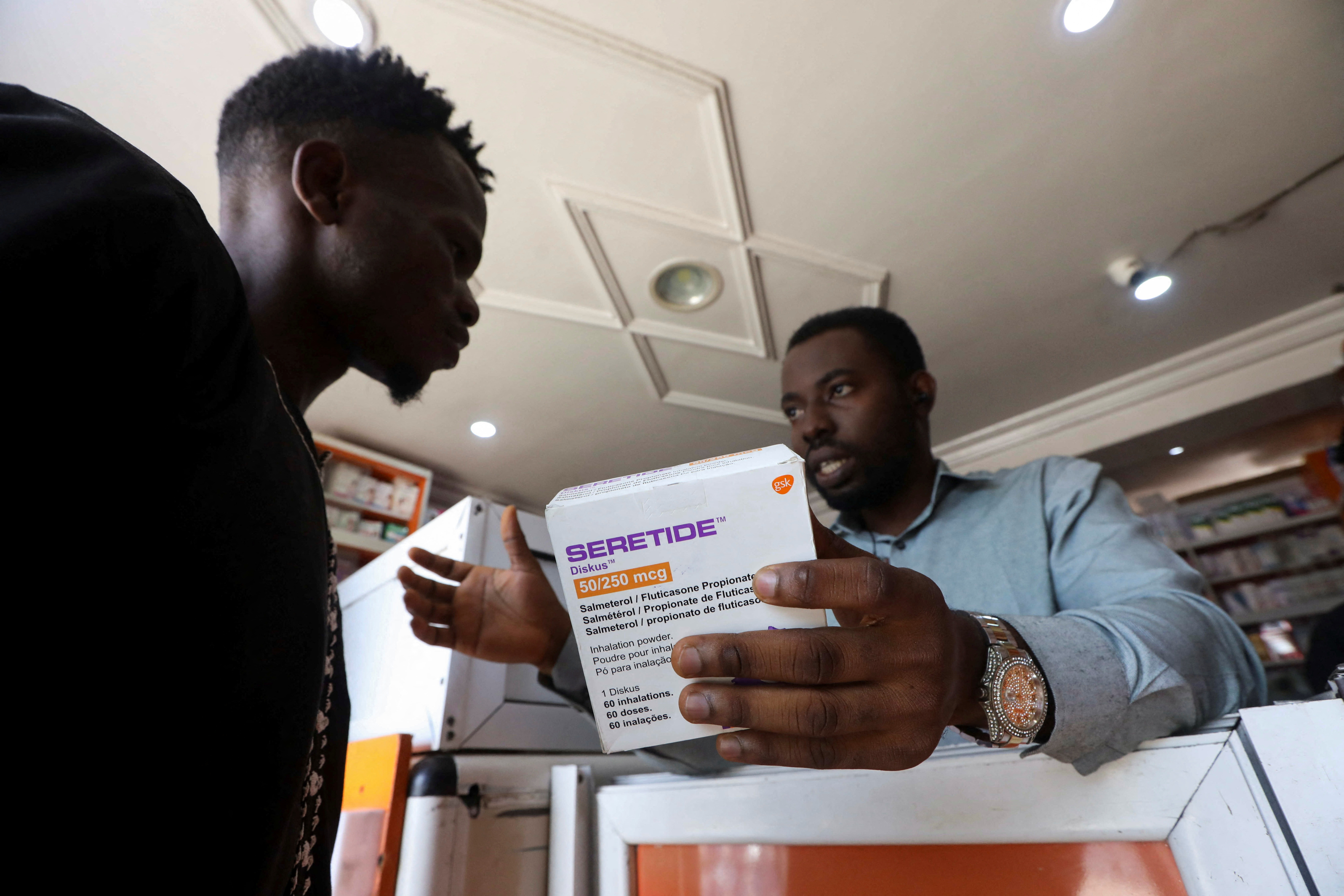 Sodiq Ajibade, 29, who suffers from bouts of asthma attacks, speaks to a pharmacist about the Seretide inhaler at a pharmacy in Lagos