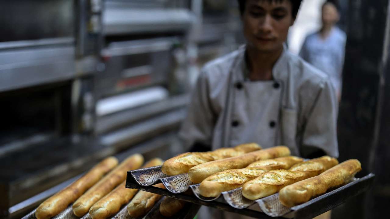 A baker holds up trays of baguettes at the Hoan Boulangerie bakery shop in Hanoi
