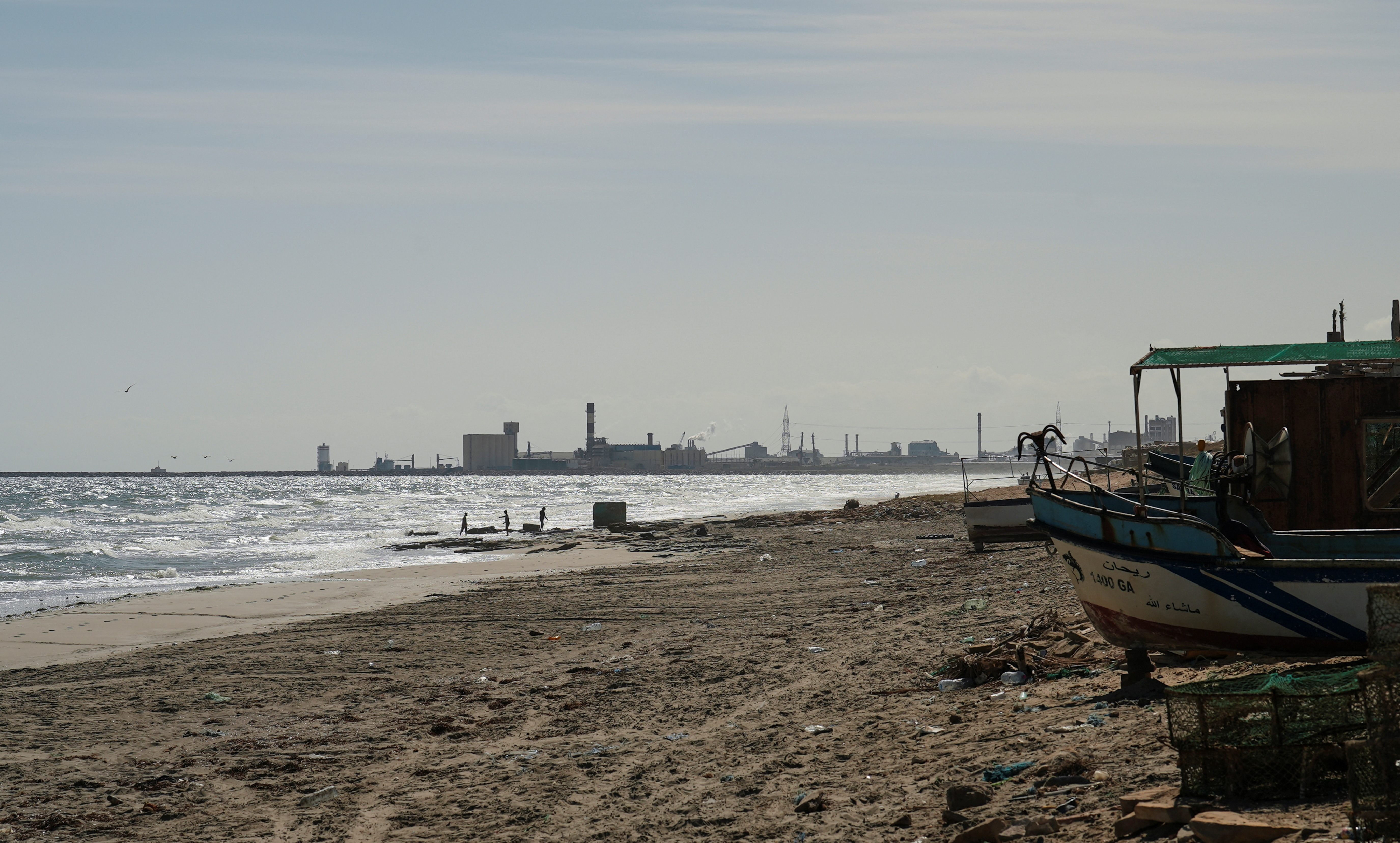 Children play on the beach with the Tunisian Chemical Group’s (CGT) phosphate complex visible in the background, in Gabes