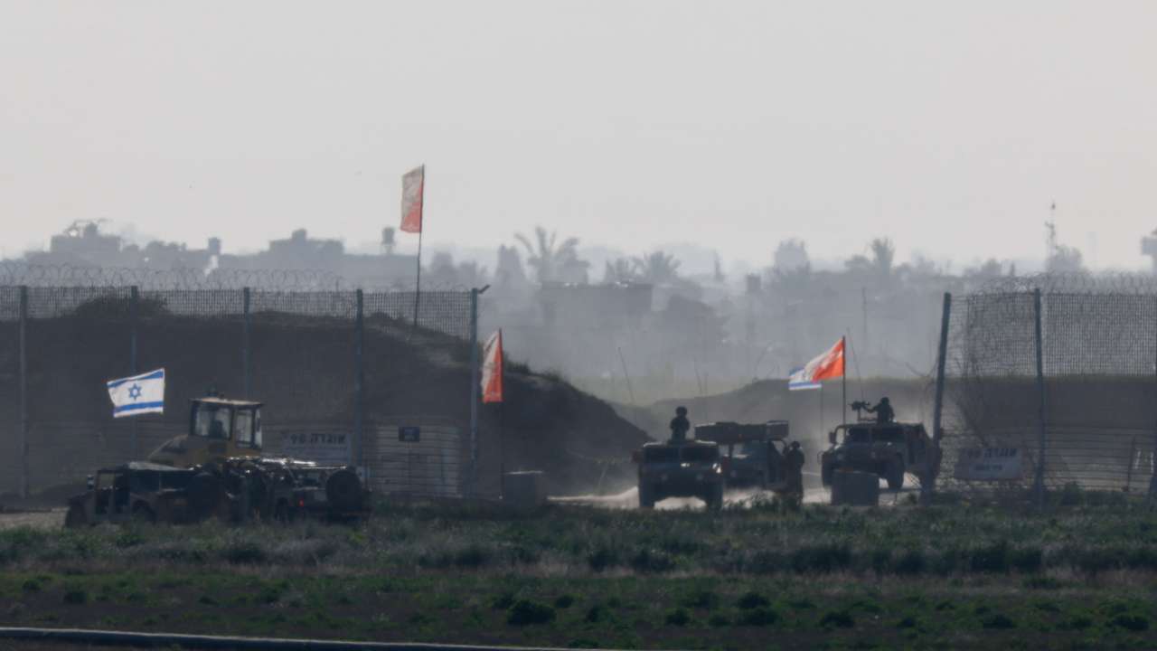 Israeli military vehicles move out from the Gaza Strip, as seen from Israel