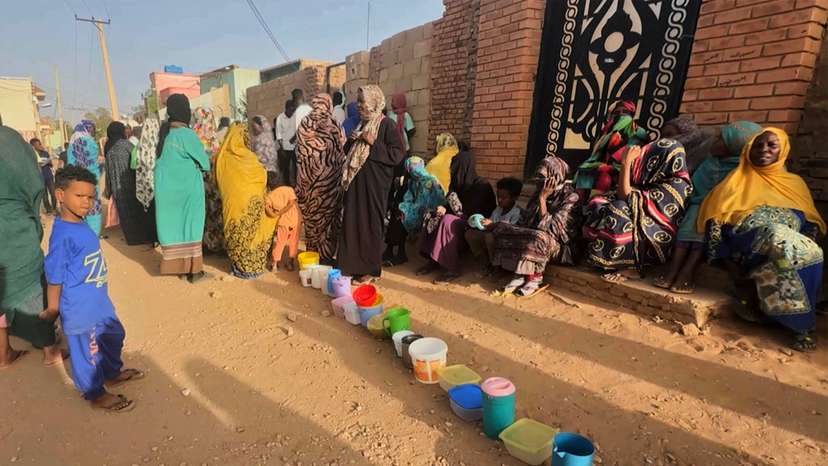 Residents collect food in containers in Omdurman