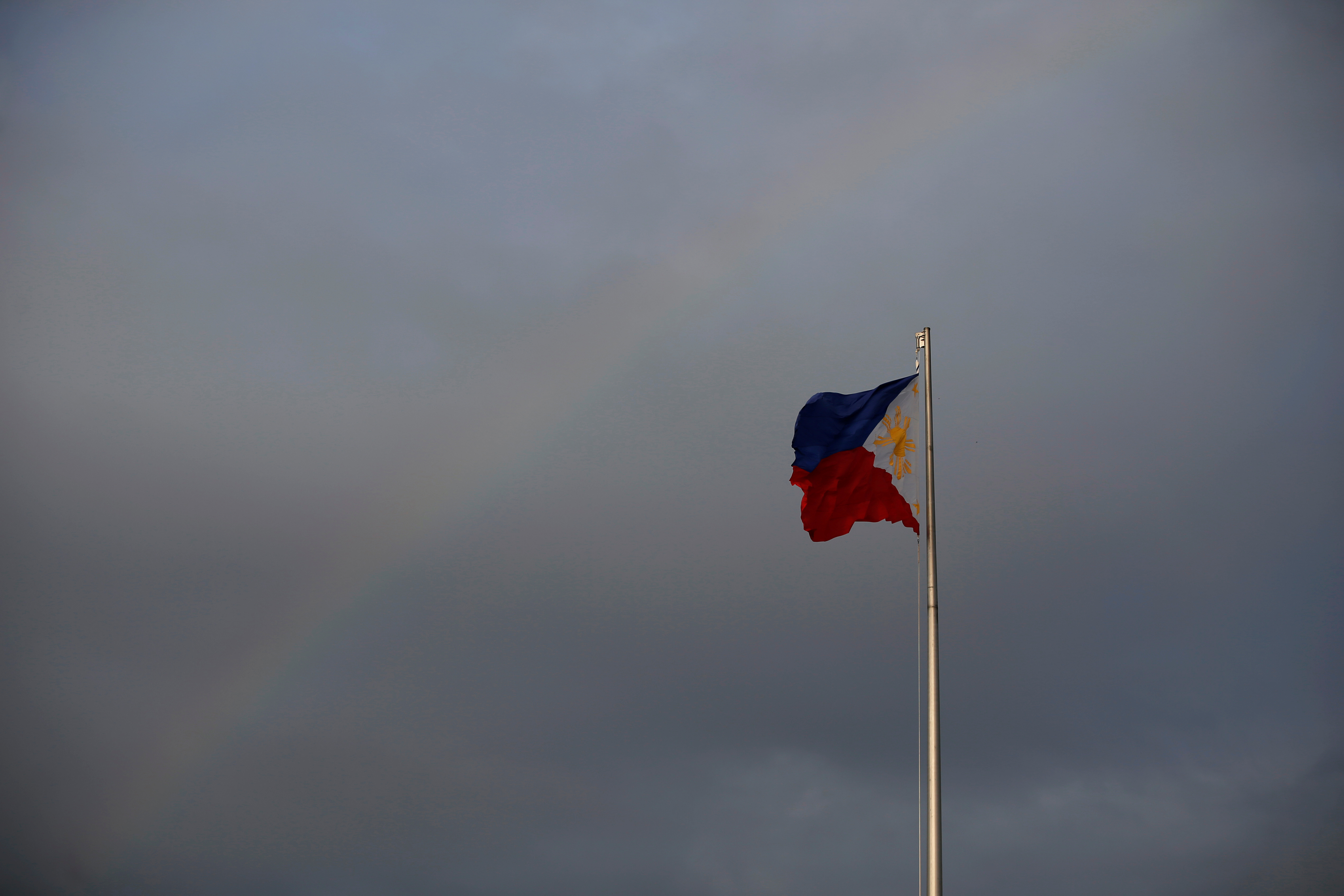 Philippines National Flag is pictured as the rainbow displays over it a day before the annual procession to celebrate Black Nazarene feast day at Quirino Grandstand in Manila