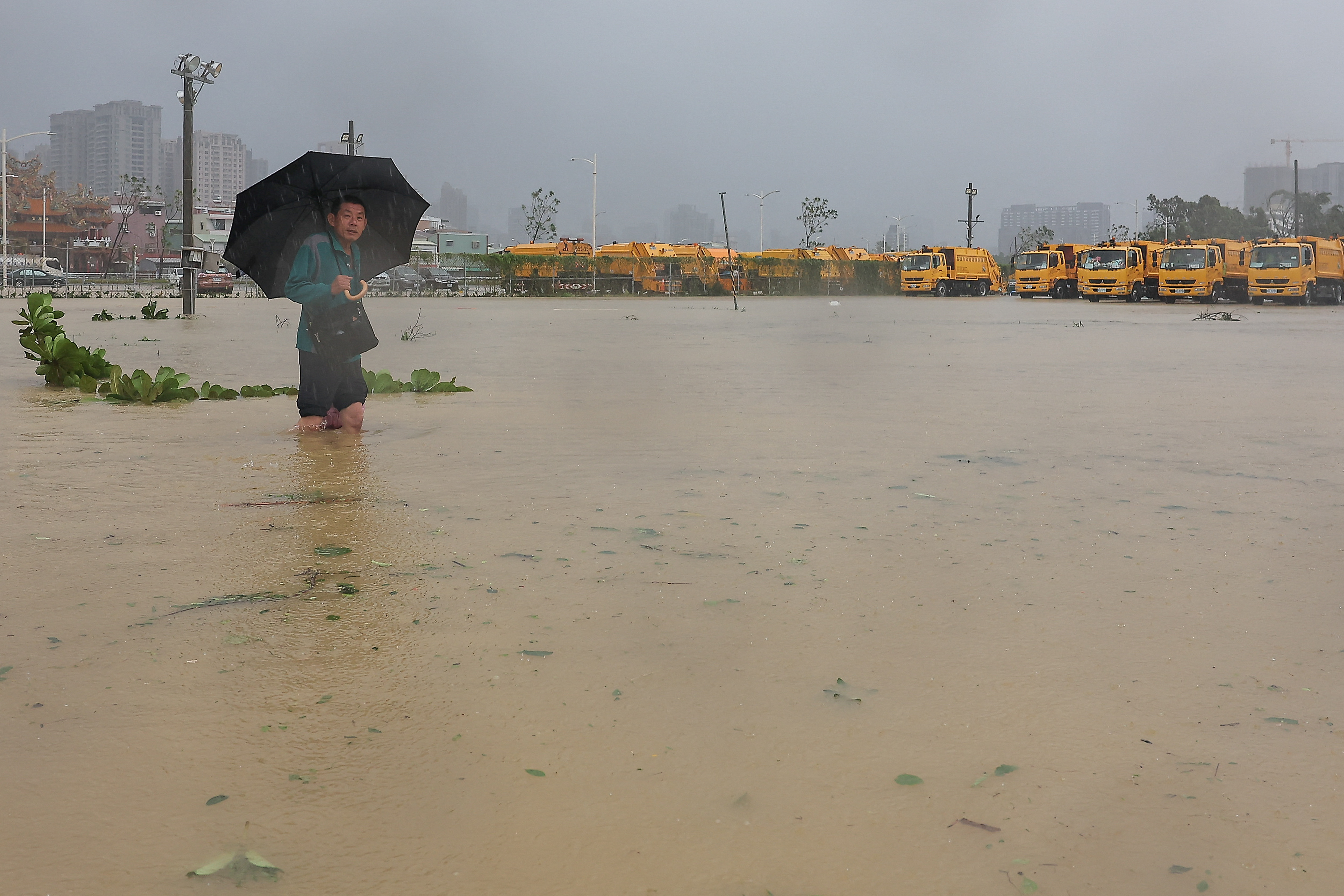 A person wades through the floodwaters to work after Typhoon Krathon made landfall in Kaohsiung