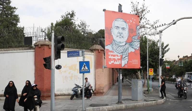 People walk past a banner with a picture of late Hamas leader Ismail Haniyeh in Tehran