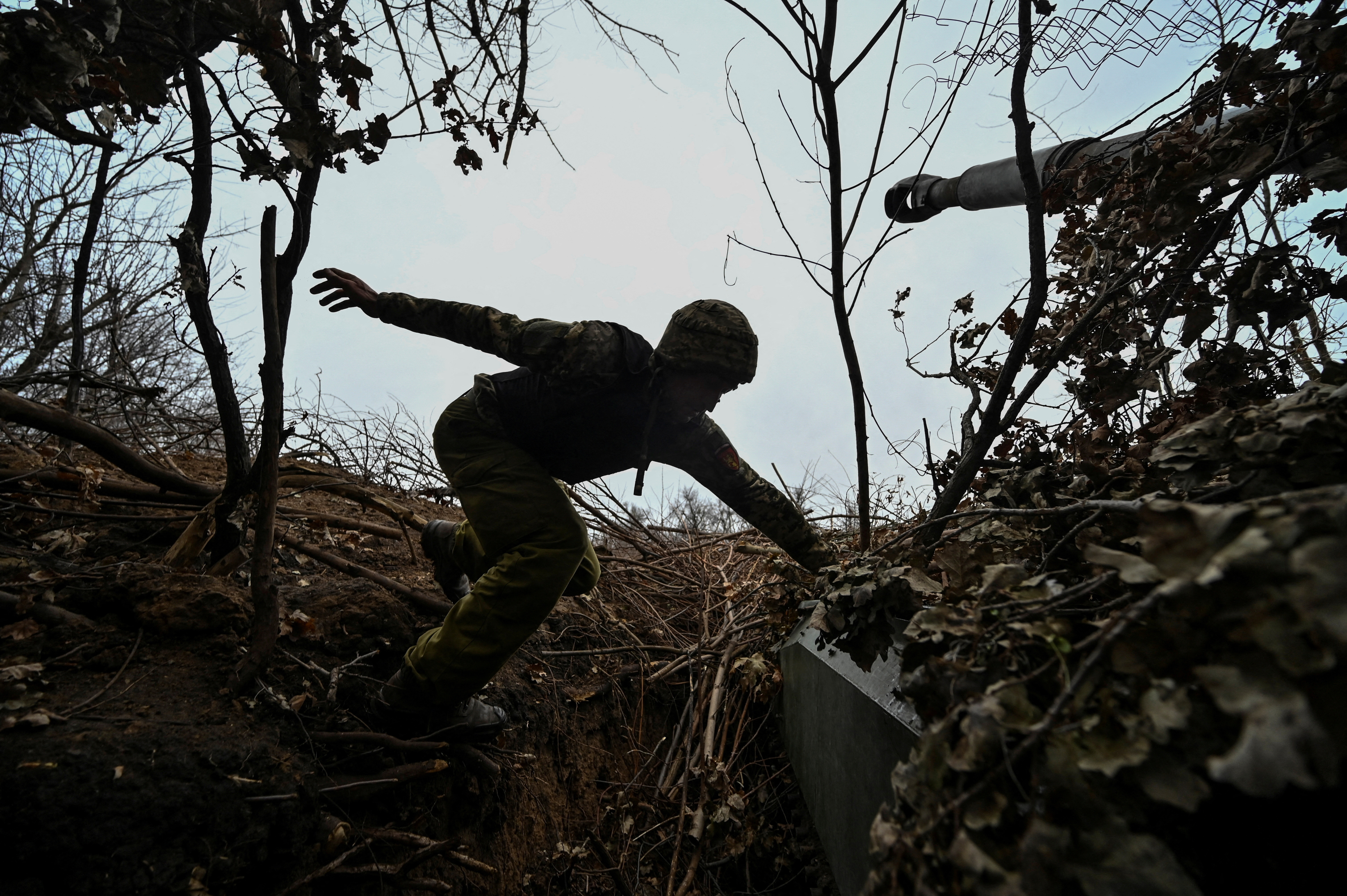 Ukrainian serviceman jumps on a self-propelled howitzer at a position on a front line in Zaporizhzhia region