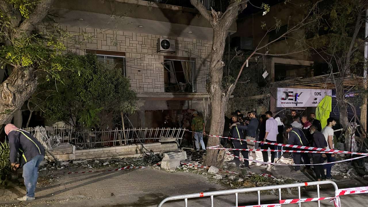 People stand at the site of an Israeli airstrike, in Damascus