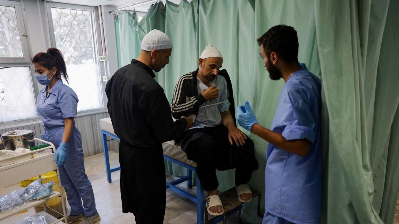 Health workers assist people at a hospital, in Sweida