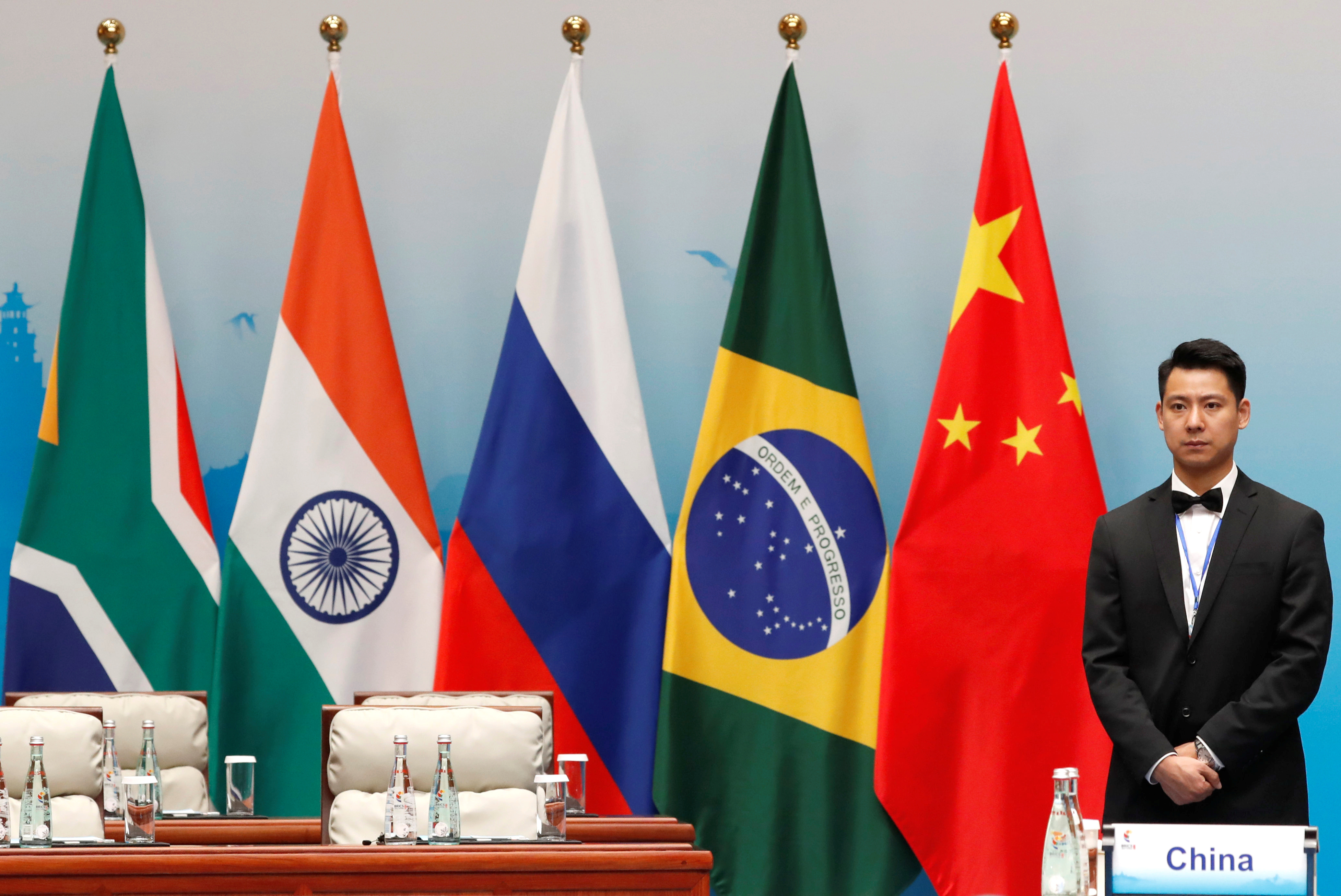 An attendant is stands next to South African, Indian, Russian, Brazilian and Chinese flags during a plenary session of BRICS Summit, in Xiamen