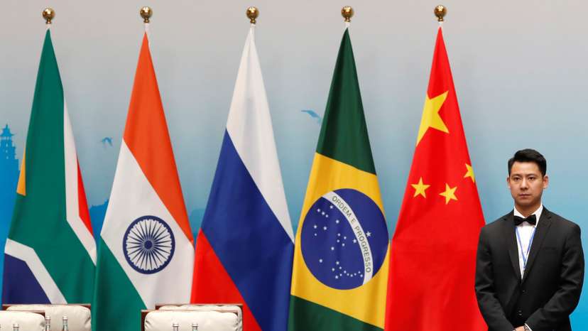 An attendant is stands next to South African, Indian, Russian, Brazilian and Chinese flags during a plenary session of BRICS Summit, in Xiamen