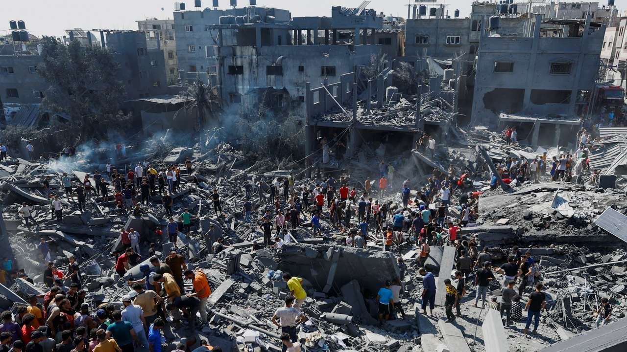 Palestinians search for casualties at the site of Israeli strikes on houses, in Khan Younis