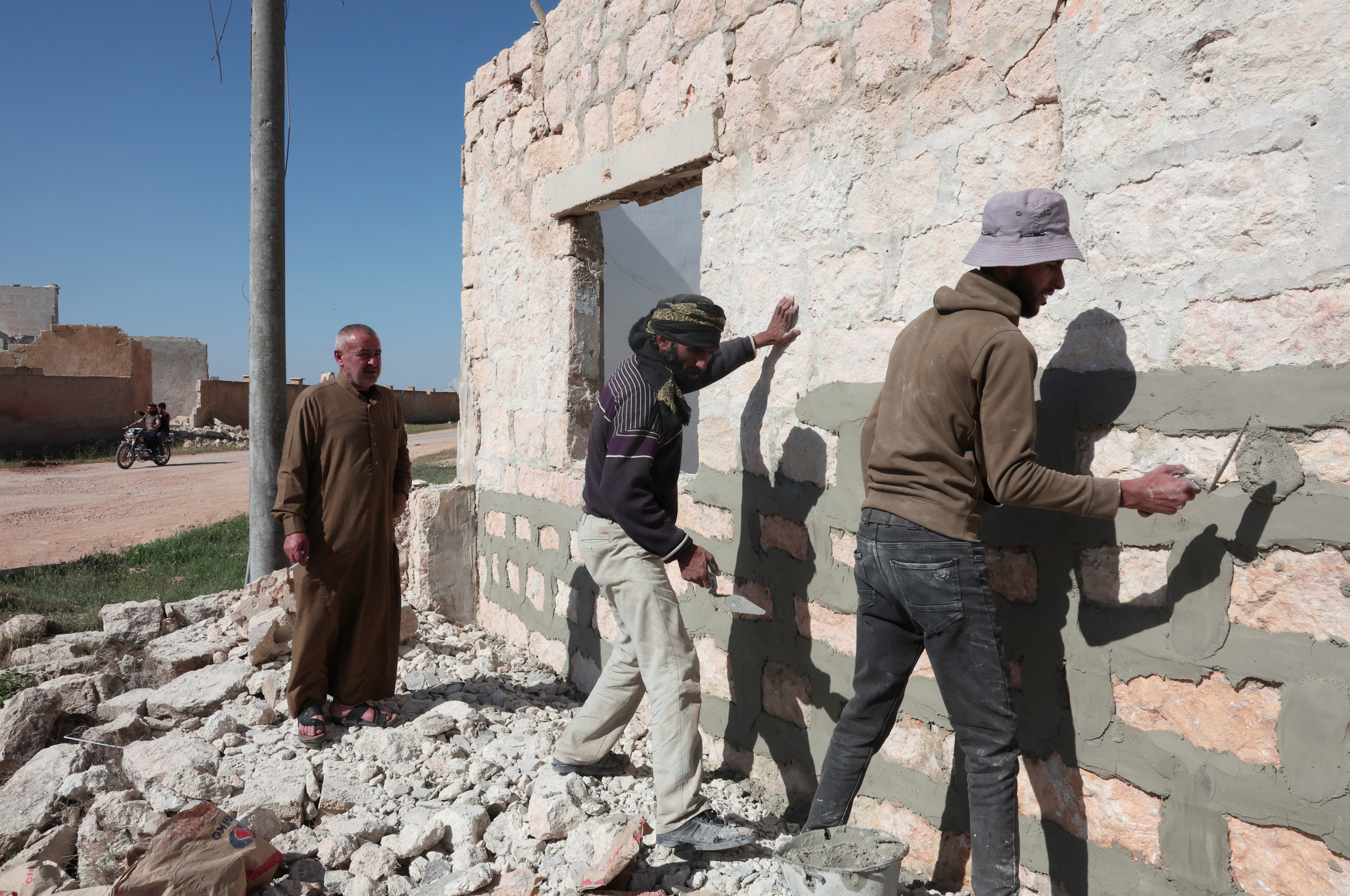 Moussa Hajj Khalil watches as the workers are rebuilding his home on Aleppo