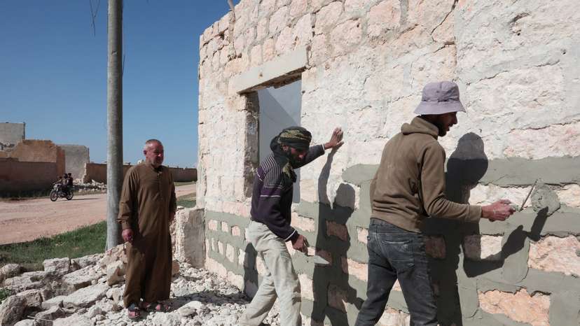 Moussa Hajj Khalil watches as the workers are rebuilding his home on Aleppo