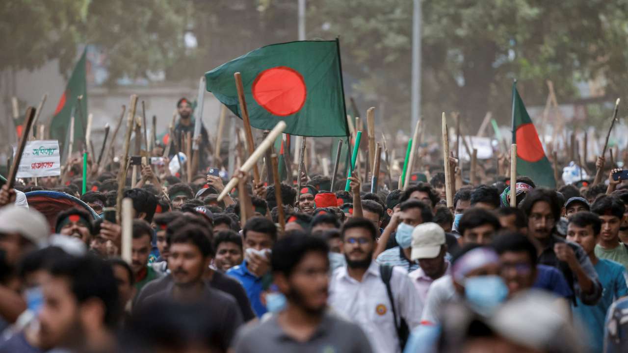 Anti-quota protesters march with Bangladeshi flags and sticks as they engage in a clash with Bangladesh Chhatra League, the student wing of the ruling party Bangladesh Awami League, at the University of Dhaka