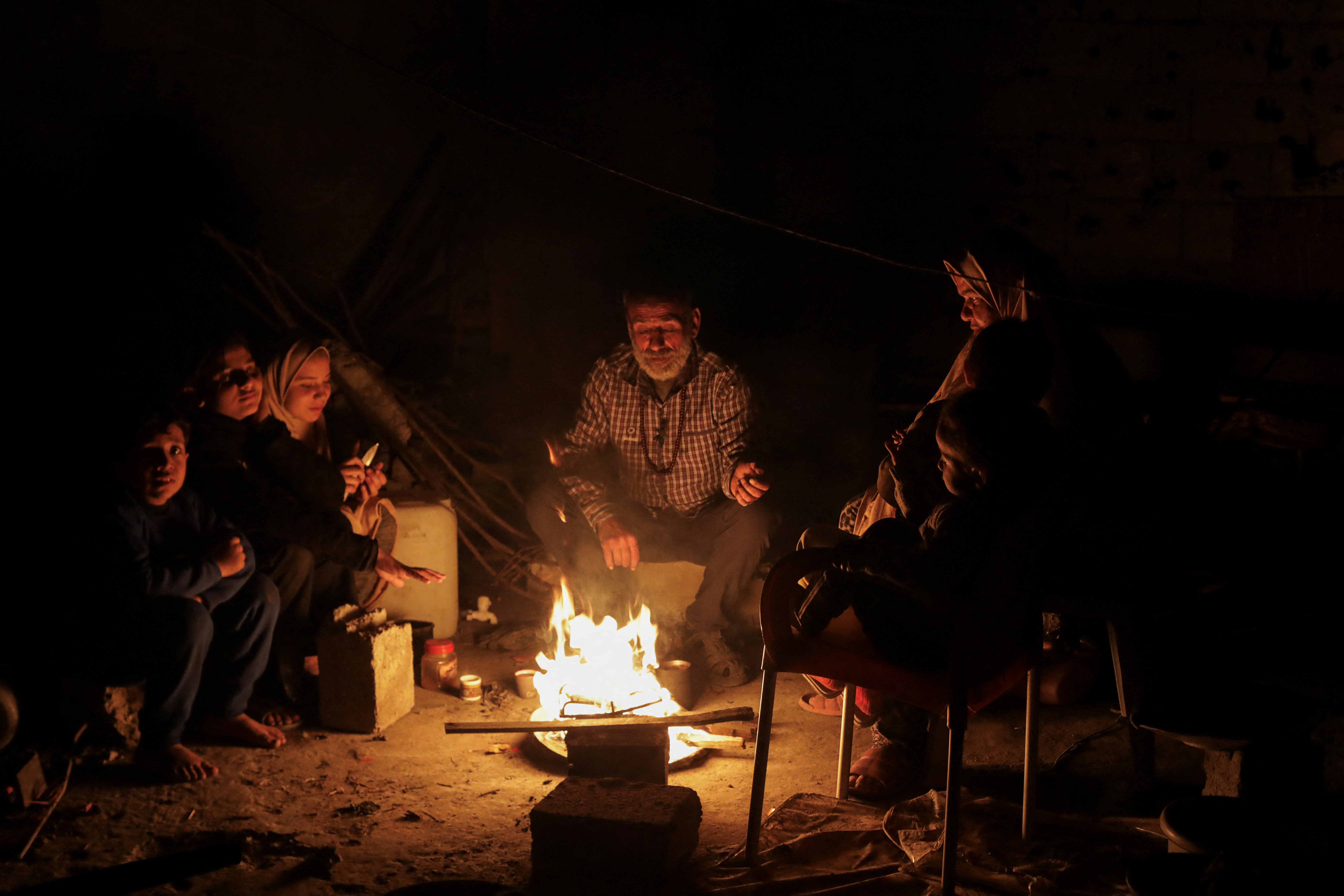 Palestinians sit next to a fire, amid a ceasefire between Israel and Hamas, in Jabalia