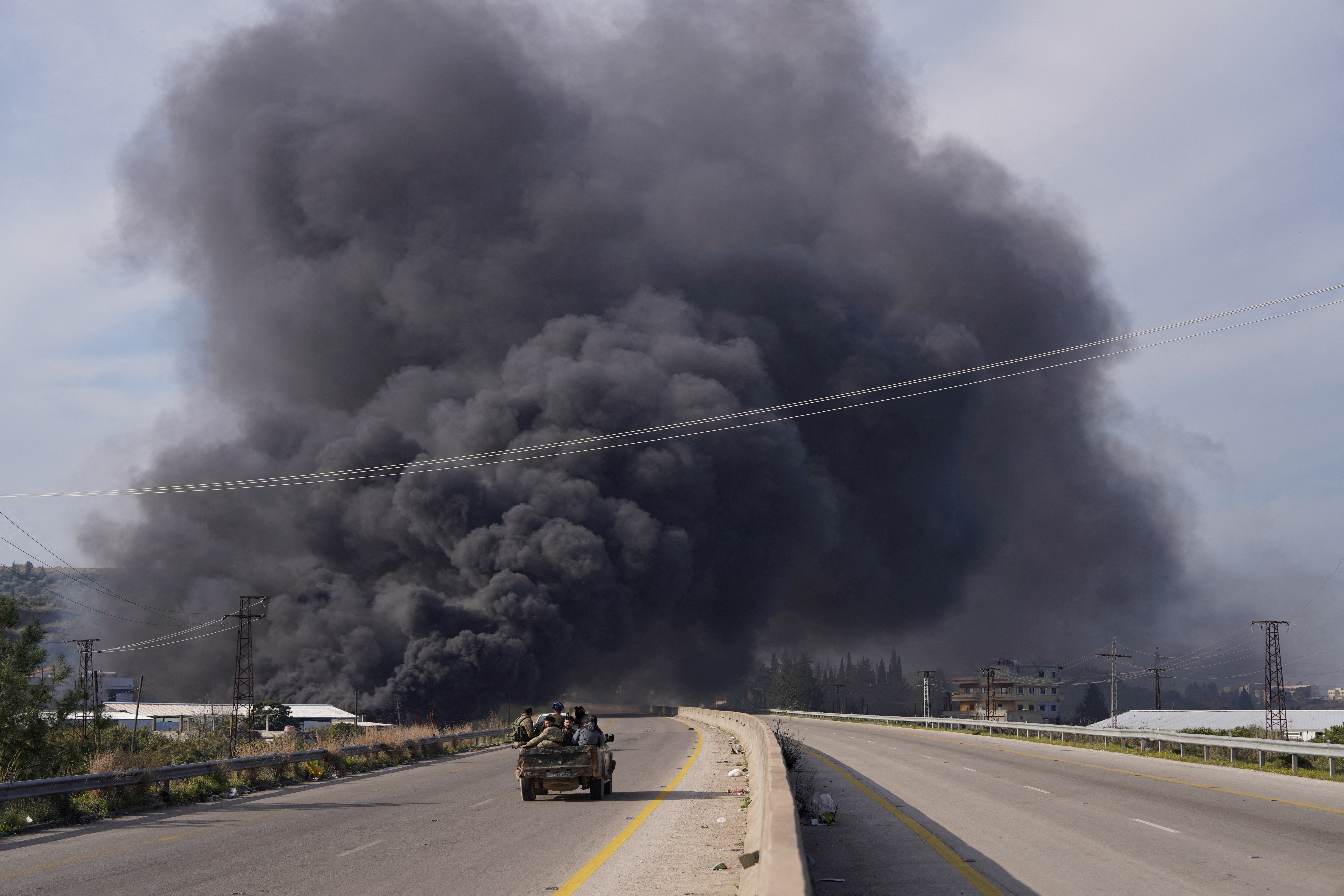 FILE PHOTO: Smoke rises while members of the Syrian forces ride on a vehicle in Latakia