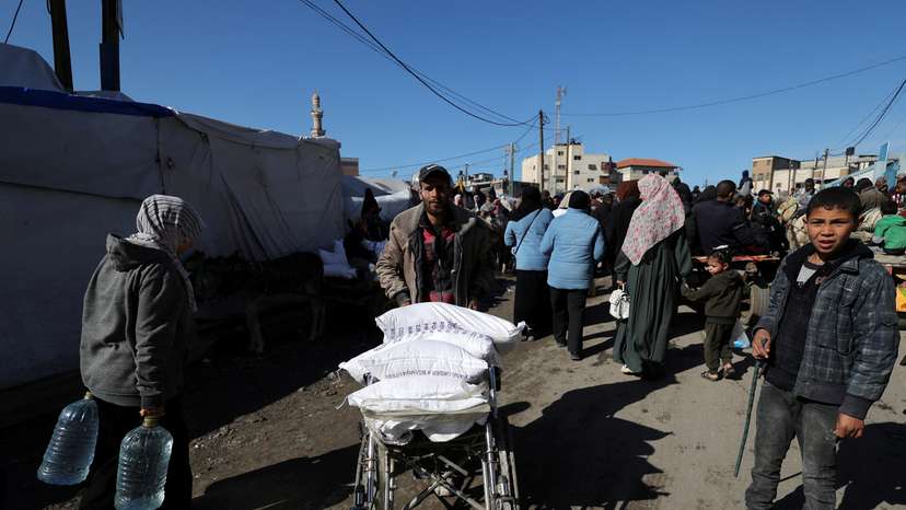 Palestinians receive bags of flour distributed by UNRWA in Rafah