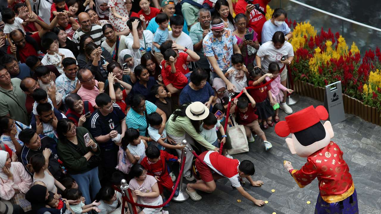 People catch coins from a God of Fortune performer during a lion dance performance on the eve of the Lunar New Year at Jewel Changi Airport in Singapore, February 16, 2026. REUTERS/Edgar Su
