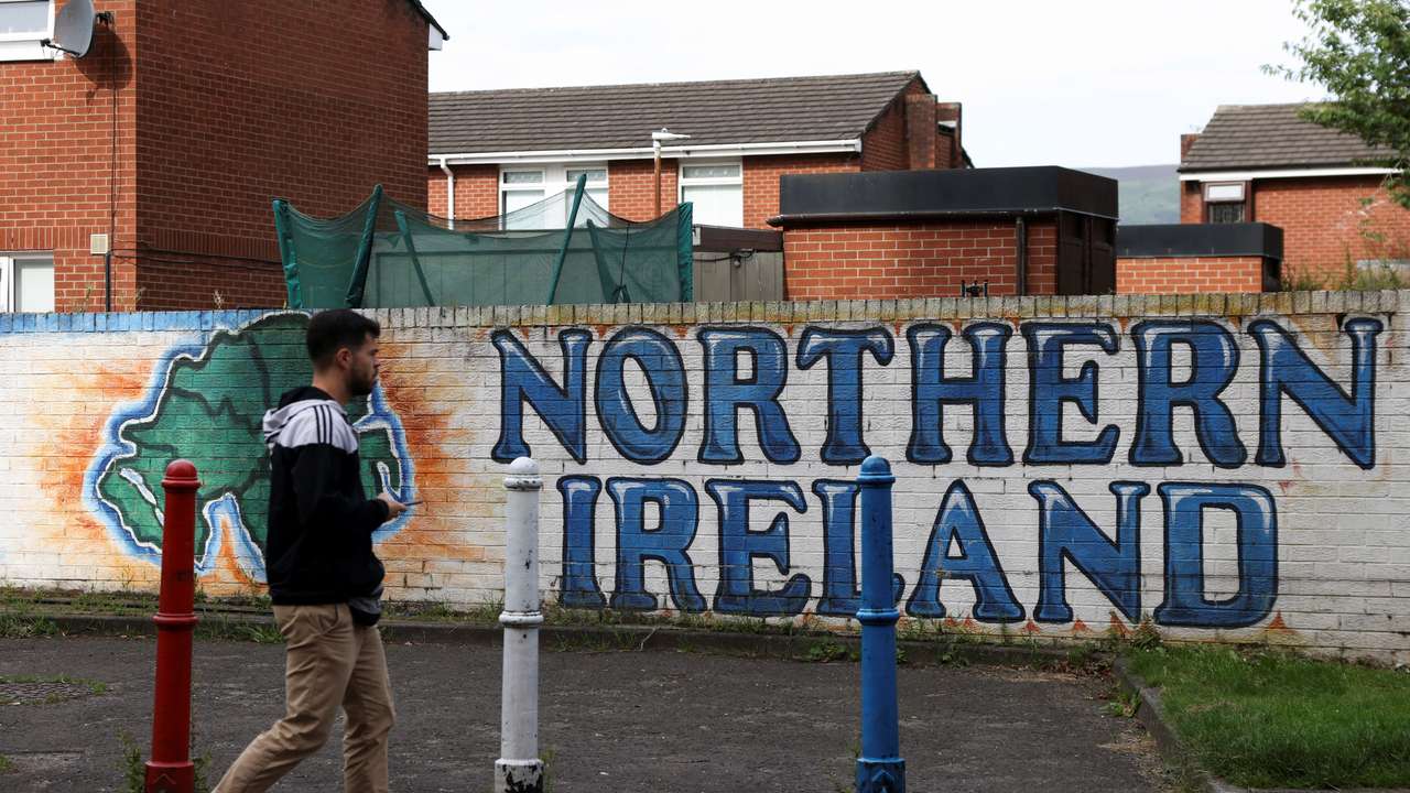 Man walks past a mural that says ‘Northern Ireland’, on Sandy Row in Belfast