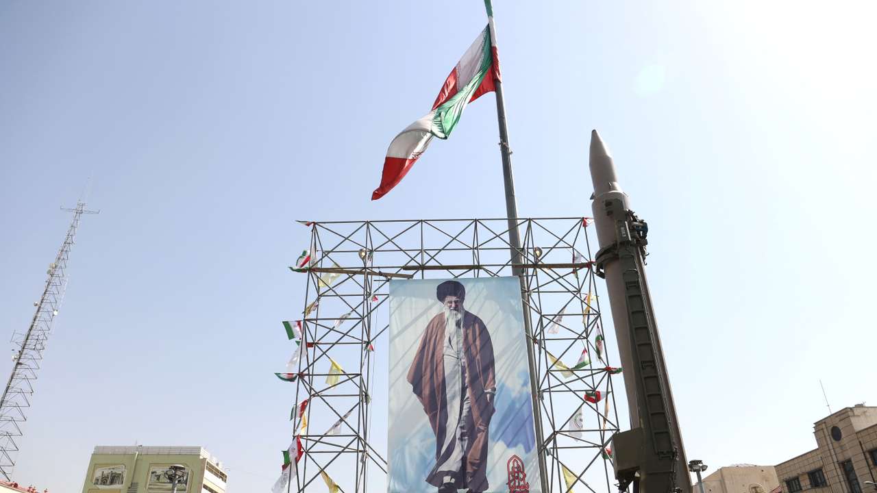 An Iranian missile system is displayed next to a banner with a picture of Iran's Supreme Leader Ayatollah Ali Khamenei and the late Lebanon's Hezbollah leader Hassan Nasrallah, in a street in Tehran