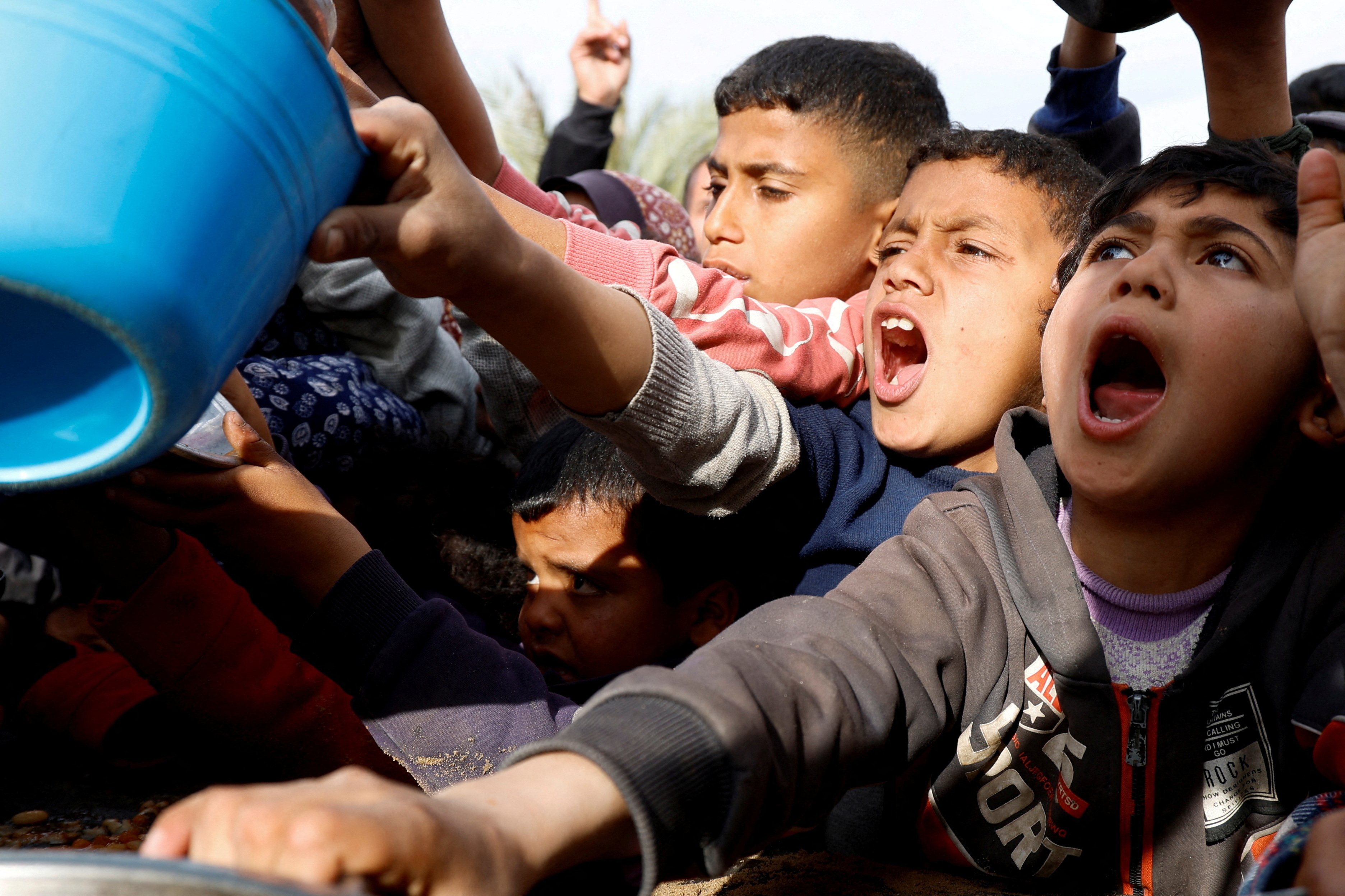 Palestinians gather to receive food cooked by a charity kitchen, in Khan Younis