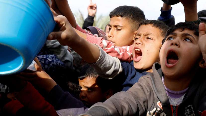 Palestinians gather to receive food cooked by a charity kitchen, in Khan Younis