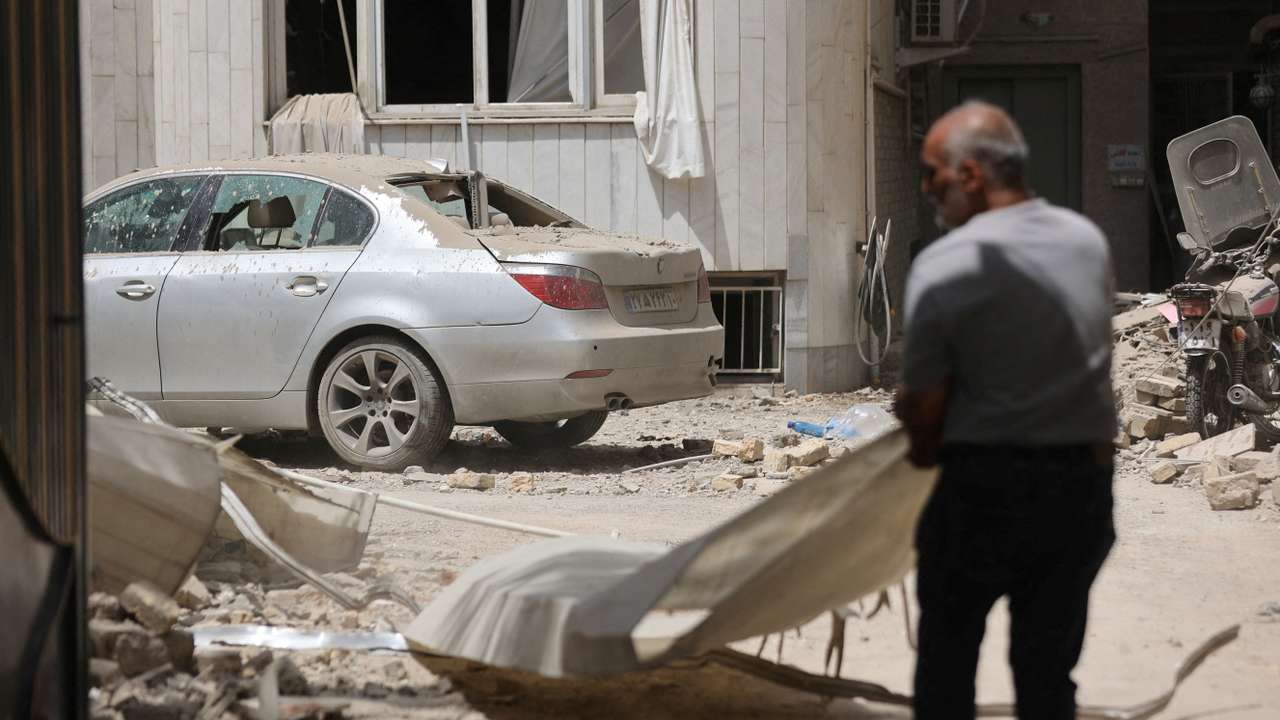 FILE PHOTO: A man stands near a damaged car at an impacted residential site, following an Israeli strike on Monday, after the ceasefire between Israel and Iran, in Tehran
