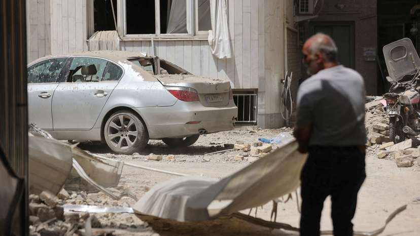 FILE PHOTO: A man stands near a damaged car at an impacted residential site, following an Israeli strike on Monday, after the ceasefire between Israel and Iran, in Tehran