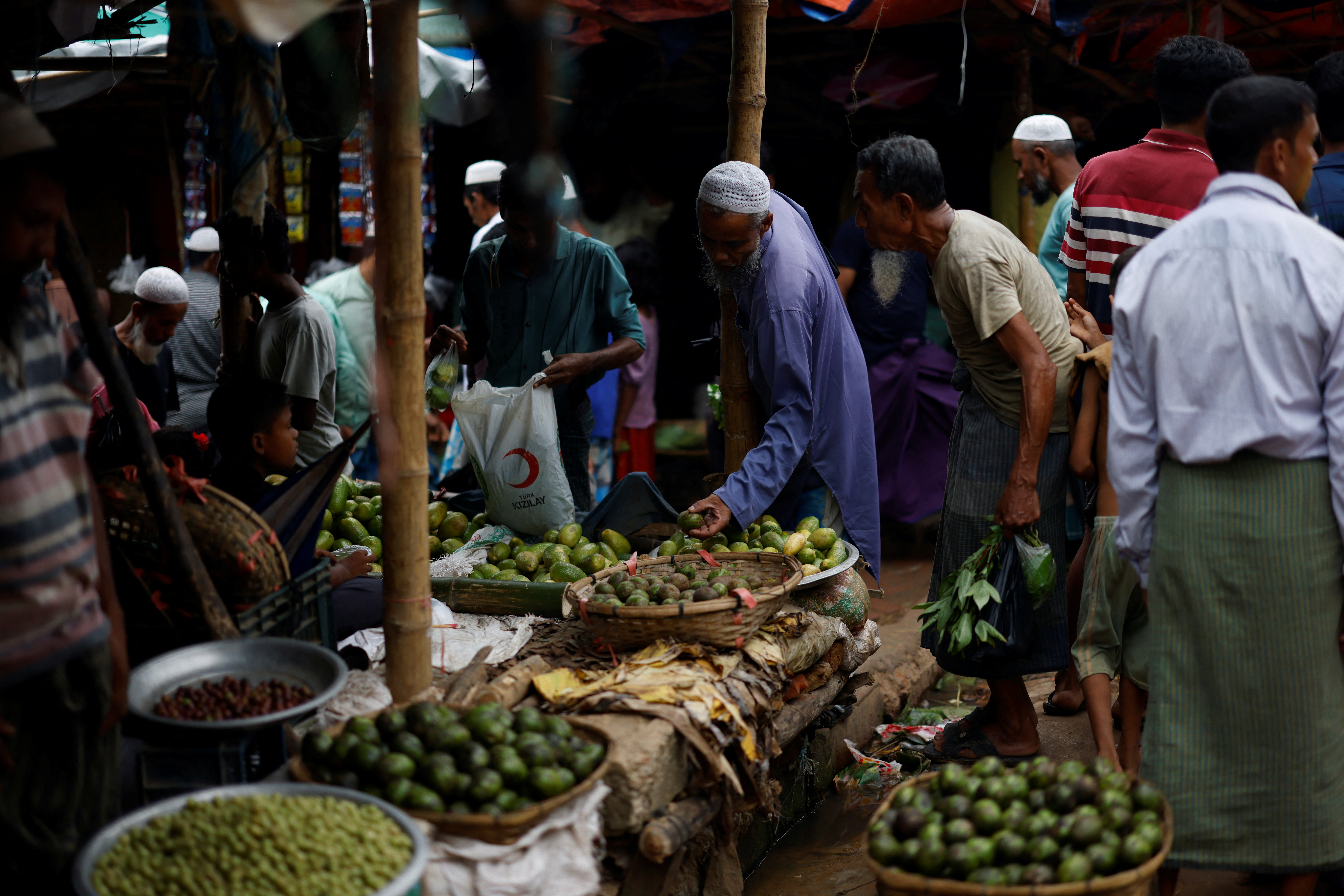 Rohingya refugees purchase vegetables from a kitchen market at a refugee camp in Cox's Bazar