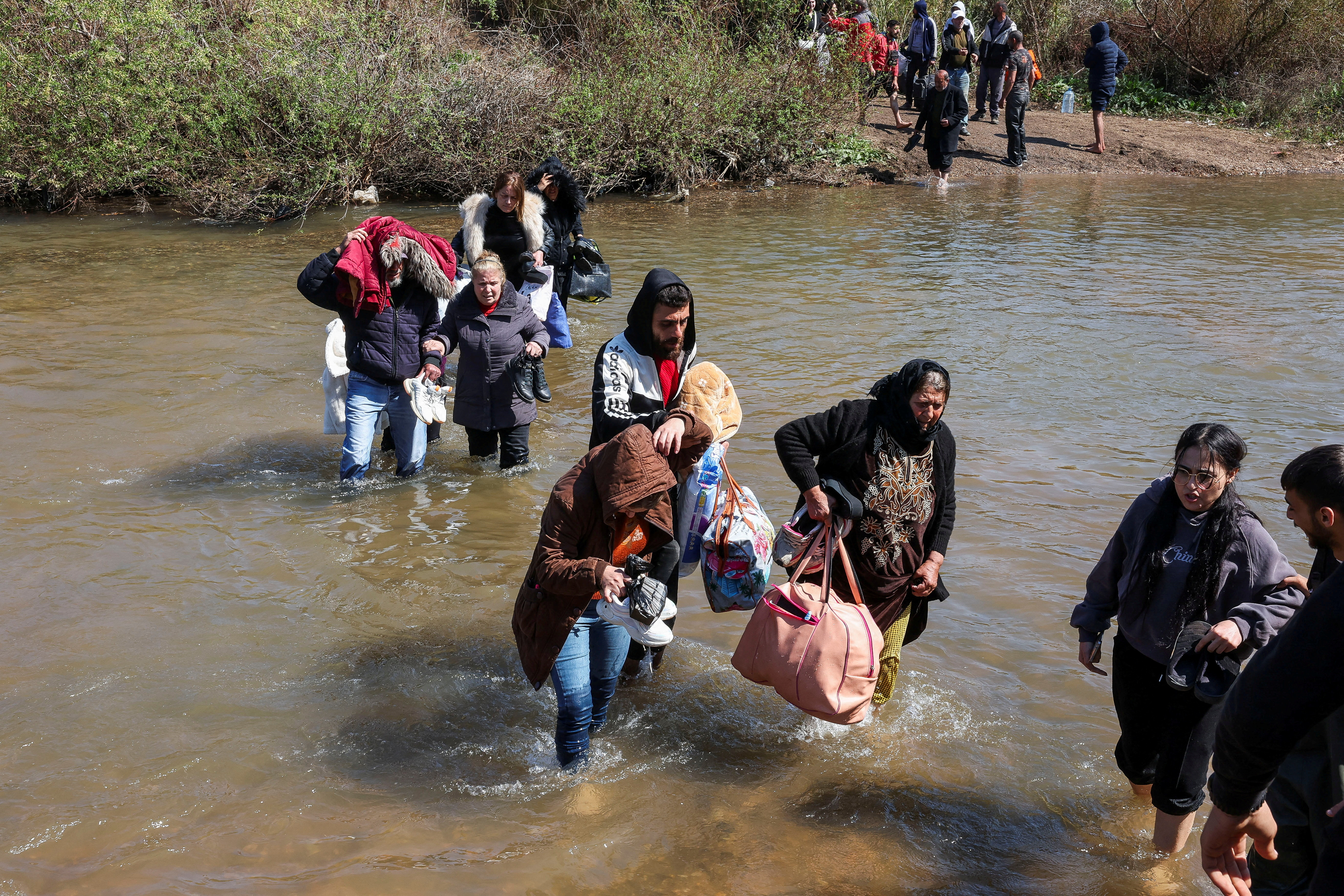 FILE PHOTO: Alawite Syrians, who fled the violence in western Syria, walk in the water of Nahr El Kabir River, in Akkar
