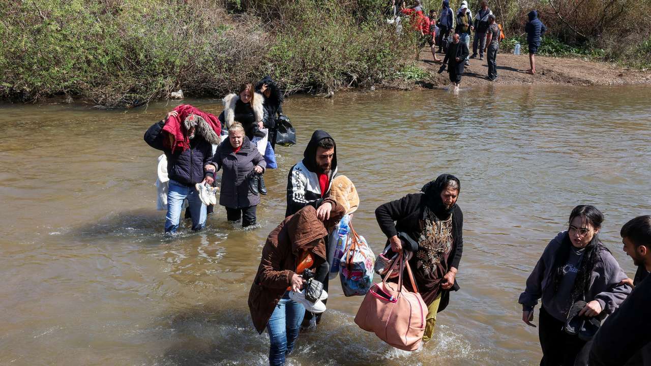 FILE PHOTO: Alawite Syrians, who fled the violence in western Syria, walk in the water of Nahr El Kabir River, in Akkar